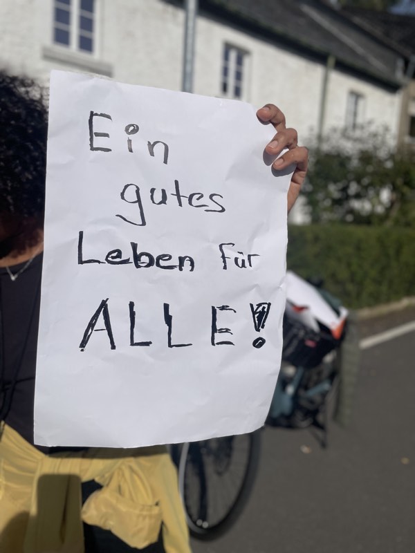 Teilnehmerin hält ein Blatt mit der Aufschrift „Ein gutes Leben für ALLE!“ hoch